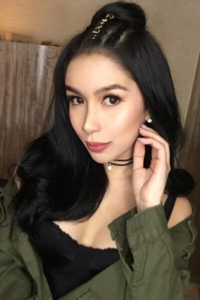 Julya, an Indonesian girl, poses with braided hair and a stylish olive jacket. Malay Escort KL Escort Malaysia Escort