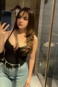 Woman in black top and jeans taking a mirror selfie.